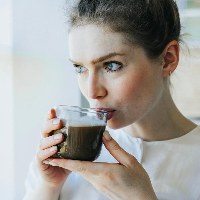 Kvinde drikker kaffe lavet på BKI kaffemaskine til erhverv