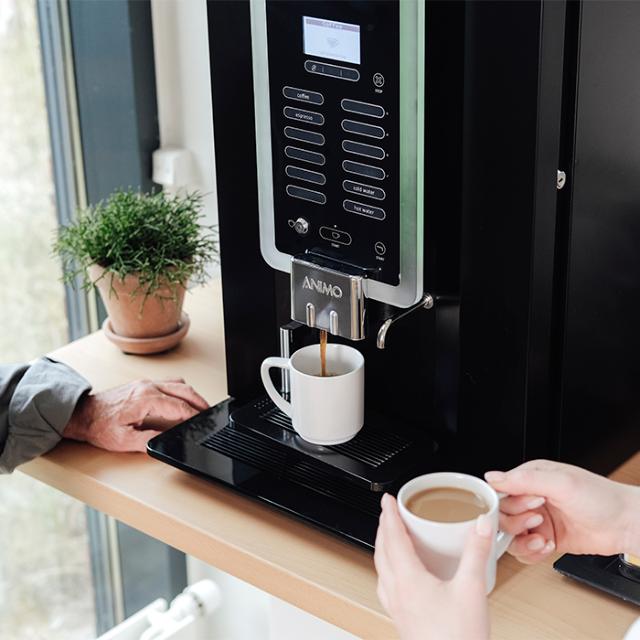 Kvinde trækker kaffe fra kaffemaskine med instant kaffe