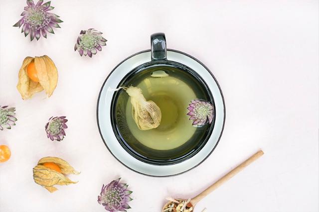 Kop grøn te med blomster til restauranter og caféer