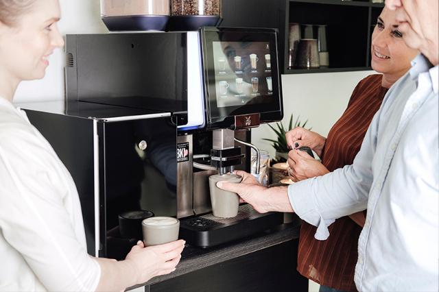 Kolleger drikker kaffe af leaset eller lejet kaffeautomat