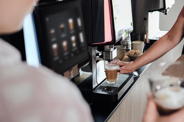 kvinde laver kaffe fra leaset eller lejet kaffeautomat