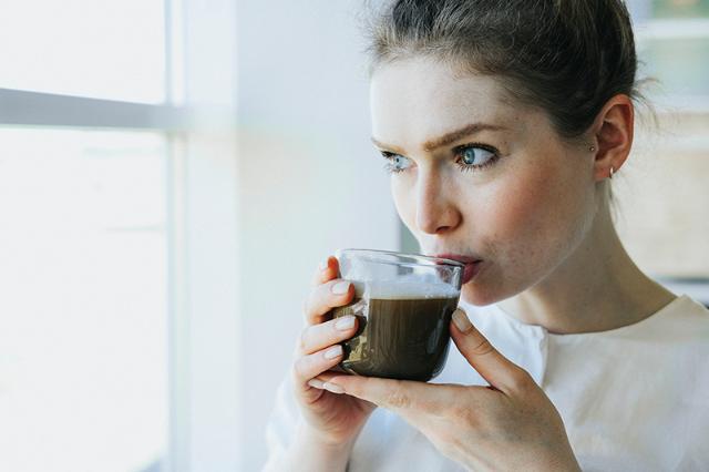 Kvinde drikker kaffe fra kaffemaskine med instant kaffe